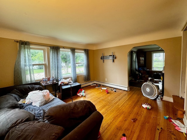 living room featuring a healthy amount of sunlight, wood-type flooring, and a baseboard heating unit