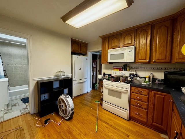 kitchen featuring decorative backsplash, light hardwood / wood-style floors, and white appliances