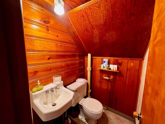 bathroom with wood walls, sink, vaulted ceiling, toilet, and wood ceiling