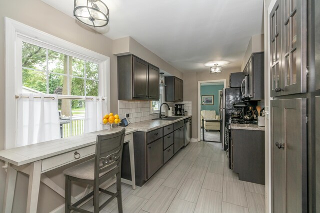 609 3rd St, Muskegon, MI 49445 - kitchen featuring stainless steel appliances, decorative backsplash, a sink, baseboards, and glass insert cabinets