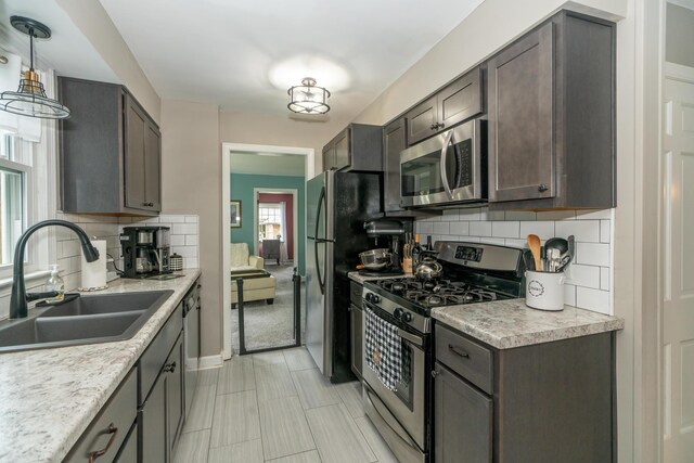 609 3rd St, Muskegon, MI 49445 - kitchen featuring appliances with stainless steel finishes, a sink, tasteful backsplash, and light countertops