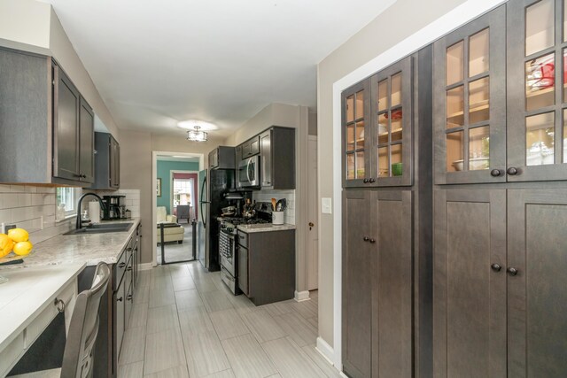 609 3rd St, Muskegon, MI 49445 - kitchen featuring stainless steel appliances, a sink, decorative backsplash, light countertops, and baseboards