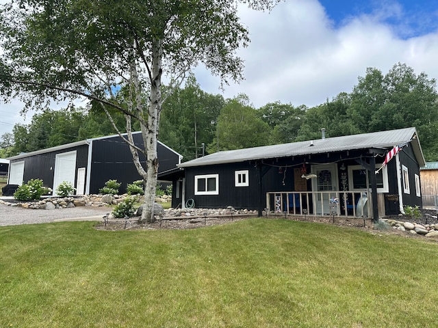 back of property with covered porch, an outbuilding, and a yard