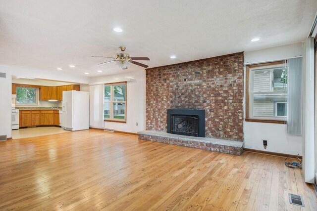 2973 Round Lake Hwy, Manitou Beach, MI 49253 - unfurnished living room with light wood finished floors, ceiling fan, baseboards, recessed lighting, and a brick fireplace