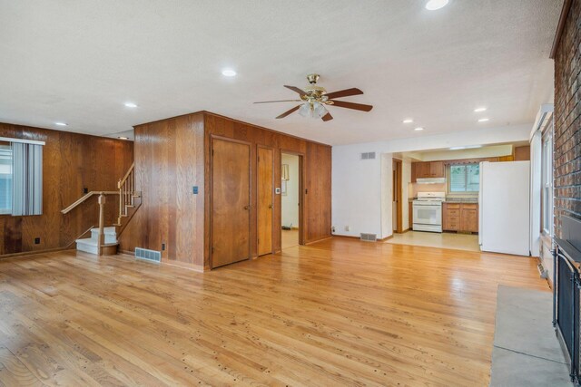 2973 Round Lake Hwy, Manitou Beach, MI 49253 - unfurnished living room featuring light wood-style flooring, stairway, a ceiling fan, wooden walls, and recessed lighting