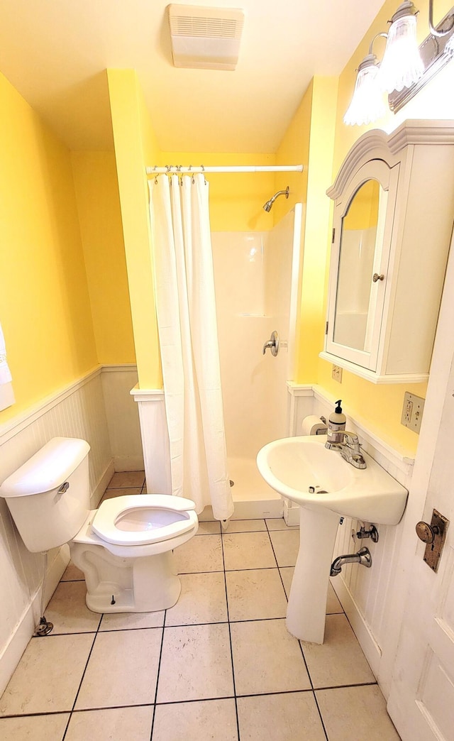 bathroom featuring toilet, a wainscoted wall, visible vents, a shower stall, and tile patterned floors