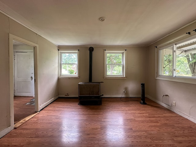 unfurnished room featuring hardwood / wood-style floors, a wood stove, and a healthy amount of sunlight