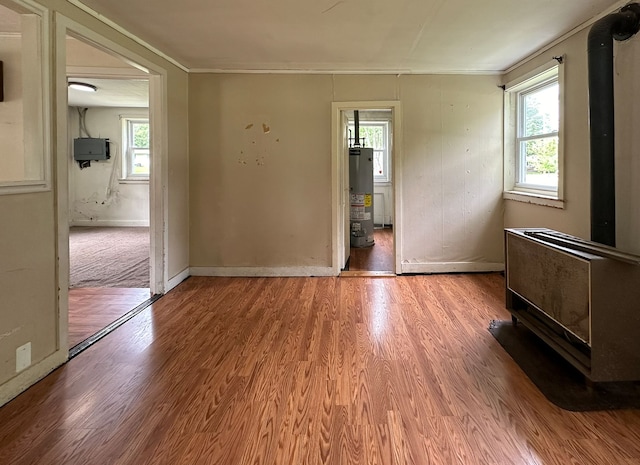 unfurnished room with hardwood / wood-style floors, a healthy amount of sunlight, and water heater