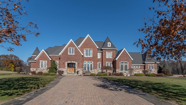 740 Greystone Dr, Chelsea, MI 48118 - colonial house featuring stone siding, a front lawn, brick siding, and driveway