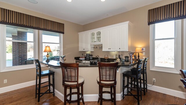 740 Greystone Dr, Chelsea, MI 48118 - kitchen featuring dark countertops, white cabinets, healthy amount of natural light, a kitchen breakfast bar, and recessed lighting