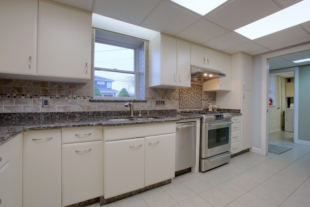 kitchen with appliances with stainless steel finishes, a paneled ceiling, sink, white cabinets, and washer / clothes dryer