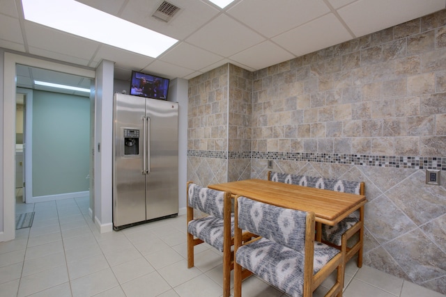 tiled dining area with a drop ceiling, tile walls, and washer / clothes dryer