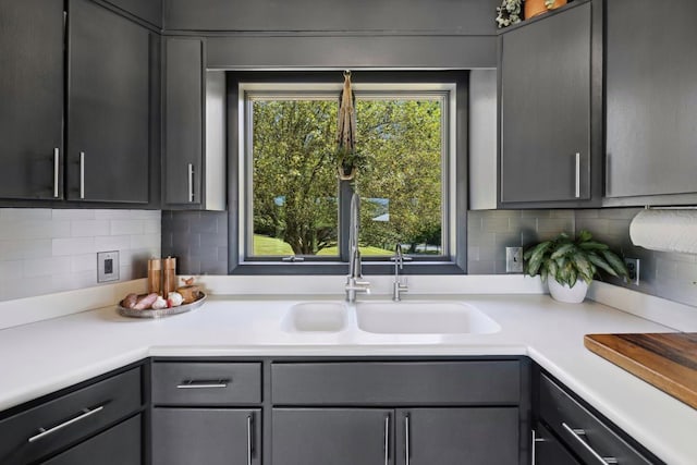 kitchen with backsplash, gray cabinets, and sink