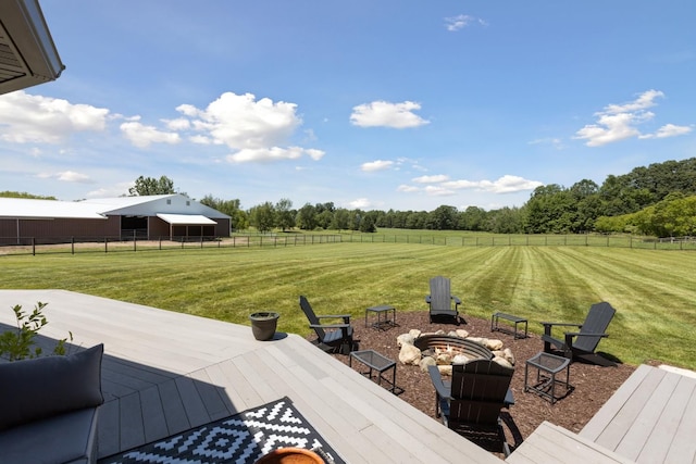 deck featuring a fire pit, a rural view, and a yard