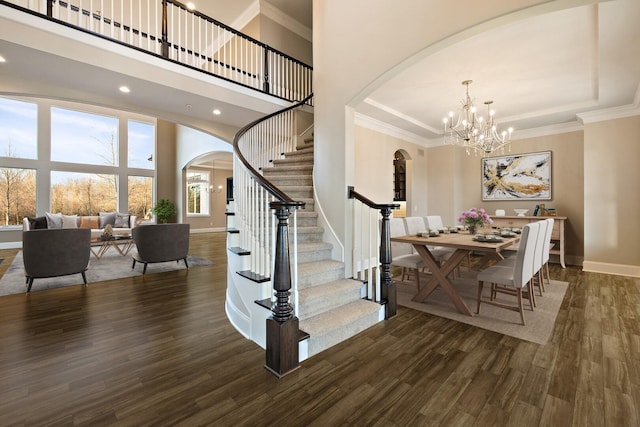 interior space with hardwood / wood-style flooring, crown molding, a towering ceiling, and an inviting chandelier