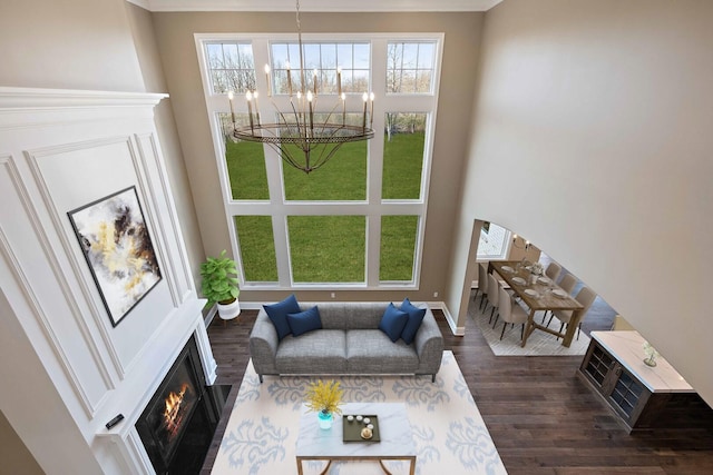 living room featuring dark wood-type flooring, a chandelier, and a high ceiling