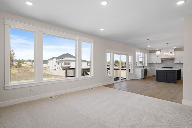 unfurnished living room with light wood-type flooring, a healthy amount of sunlight, and sink