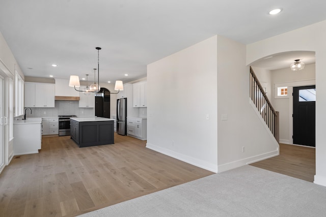 kitchen featuring white cabinets, a kitchen island, stainless steel appliances, and light hardwood / wood-style floors