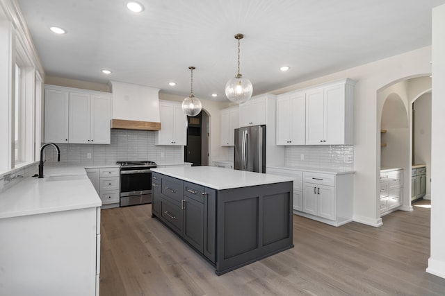 kitchen with sink, stainless steel appliances, a kitchen island, premium range hood, and white cabinets