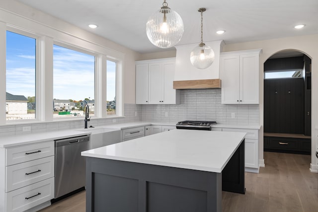 kitchen featuring decorative backsplash, stainless steel appliances, hardwood / wood-style floors, a center island, and white cabinetry