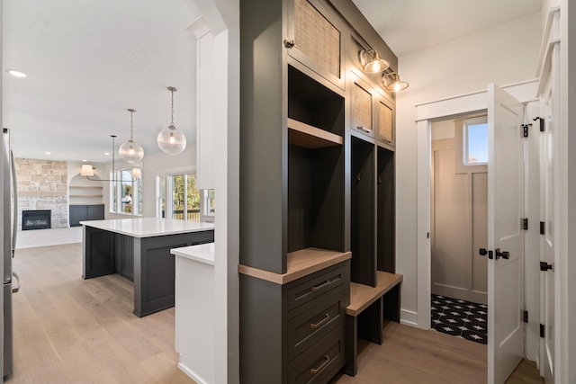 mudroom with light hardwood / wood-style flooring and a stone fireplace