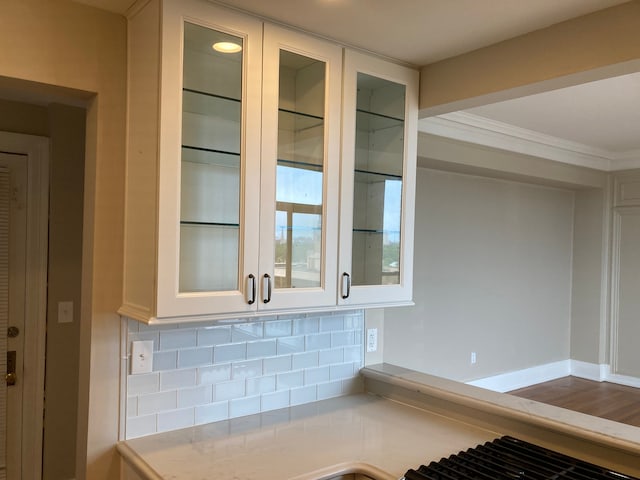 details featuring white cabinets, tasteful backsplash, and ornamental molding