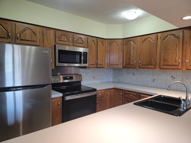 kitchen featuring decorative backsplash, appliances with stainless steel finishes, a textured ceiling, and sink