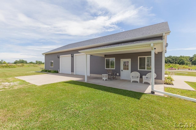 back of property with a lawn, a patio area, and a garage