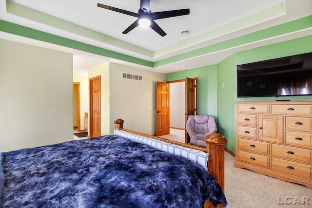 carpeted bedroom featuring ceiling fan and a raised ceiling