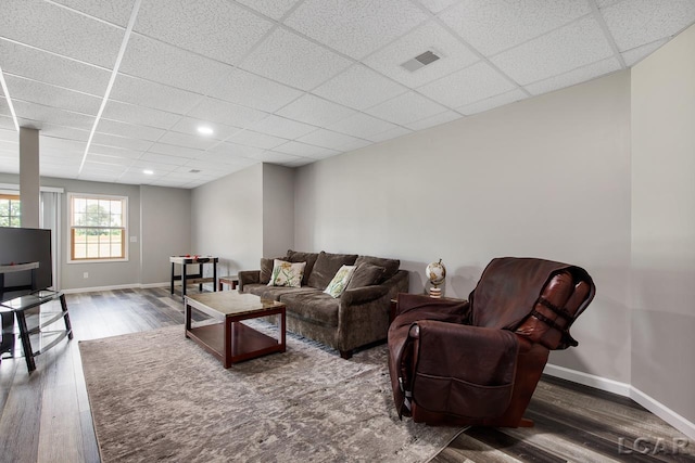 living room featuring dark hardwood / wood-style flooring and a drop ceiling