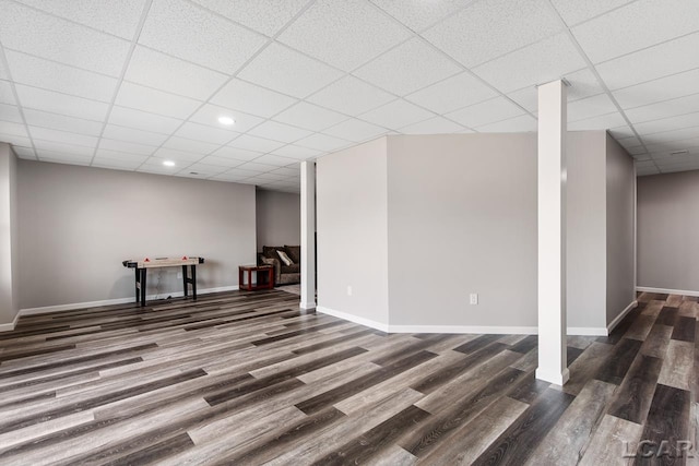 basement with a paneled ceiling and dark wood-type flooring