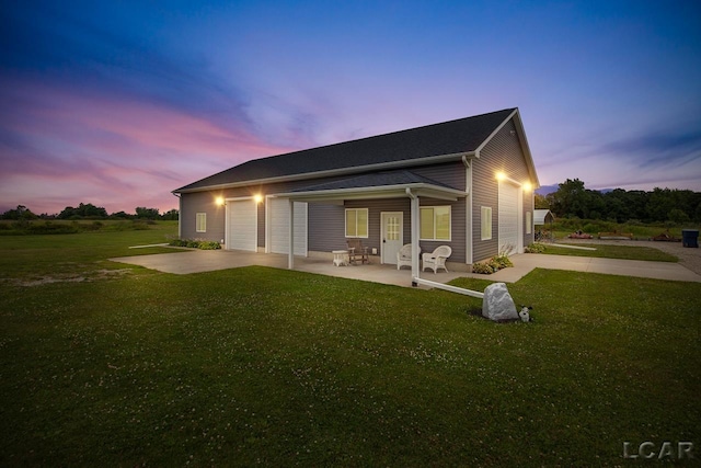 back house at dusk featuring a patio area and a yard