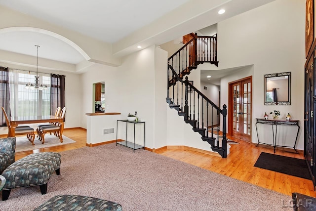 interior space with a wealth of natural light, french doors, wood-type flooring, and an inviting chandelier