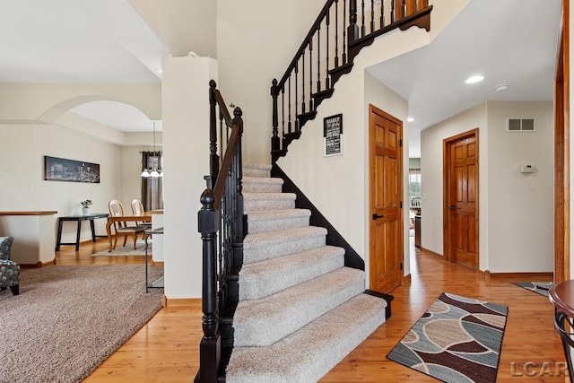 staircase with wood-type flooring and an inviting chandelier