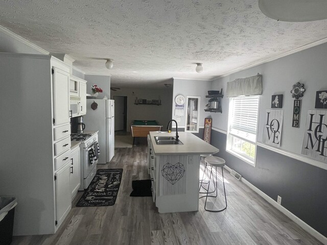 1875 Fire Rd, Twining, MI 48766 - kitchen featuring white appliances, white cabinets, a kitchen breakfast bar, a center island with sink, and sink