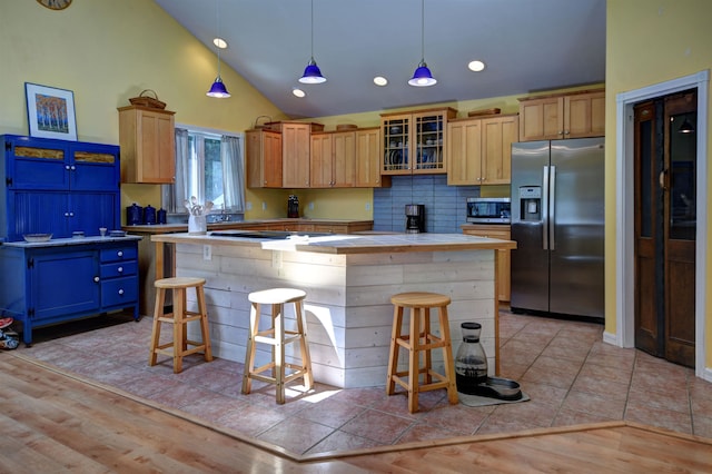 kitchen featuring light wood-type flooring, appliances with stainless steel finishes, a center island, and high vaulted ceiling