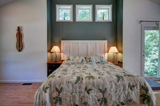 bedroom with multiple windows, lofted ceiling, and hardwood / wood-style flooring