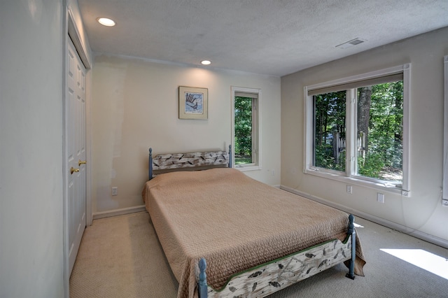 bedroom featuring light colored carpet and a textured ceiling