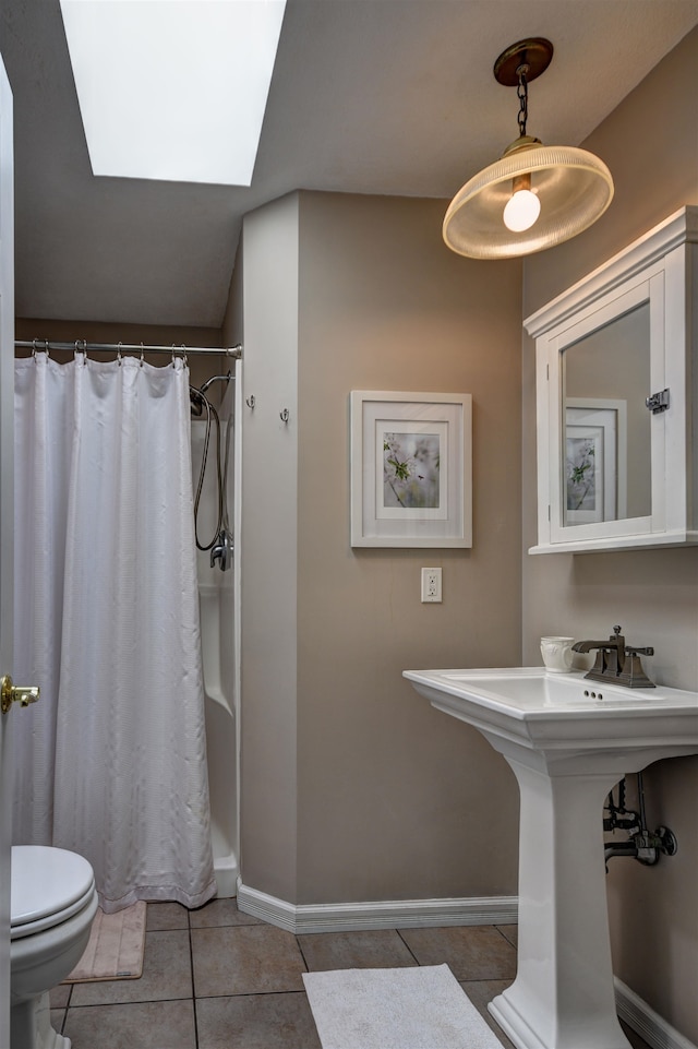 bathroom featuring tile patterned flooring, a shower with curtain, toilet, and a skylight