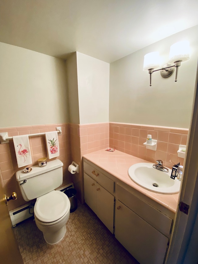 bathroom featuring tile walls, vanity, a baseboard heating unit, toilet, and tile patterned floors