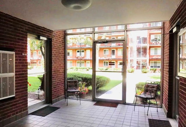 doorway with a healthy amount of sunlight, brick wall, and tile patterned floors