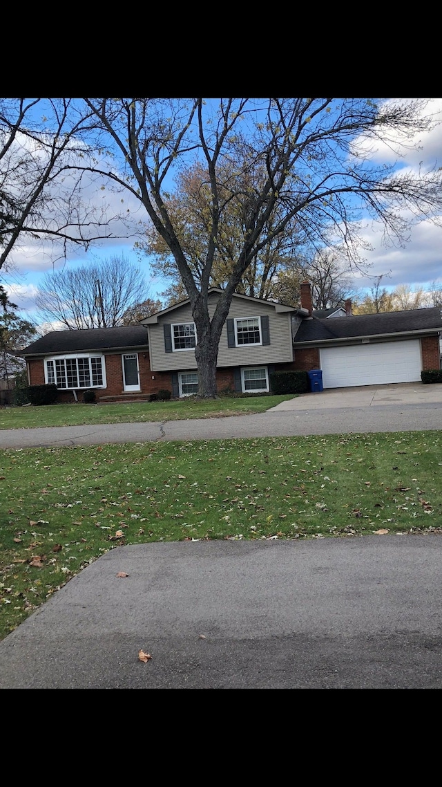 5510 Berkley Dr, Waterford, MI 48327 - tri-level home featuring a front yard, a garage, driveway, and brick siding