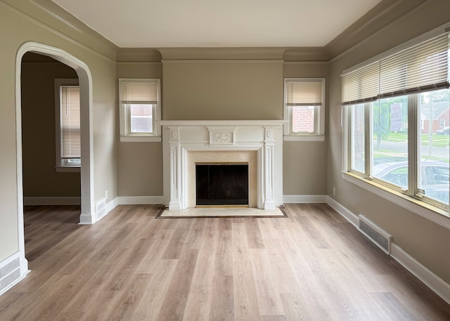 unfurnished living room with crown molding and light wood-type flooring