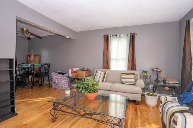 living room with beam ceiling, ceiling fan, a textured ceiling, and hardwood / wood-style flooring