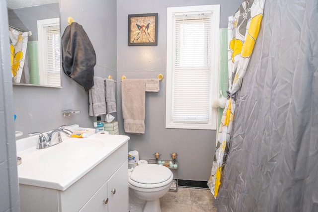 bathroom featuring tile patterned flooring, vanity, toilet, and tile walls