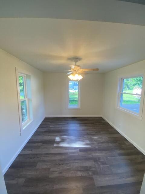 empty room with plenty of natural light, dark hardwood / wood-style floors, and ceiling fan