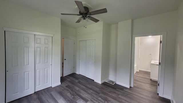 unfurnished bedroom featuring multiple closets, ceiling fan, and dark wood-type flooring