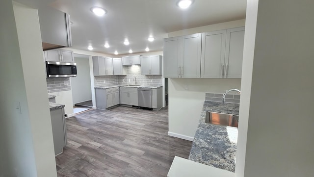 kitchen featuring appliances with stainless steel finishes, backsplash, light hardwood / wood-style flooring, and sink