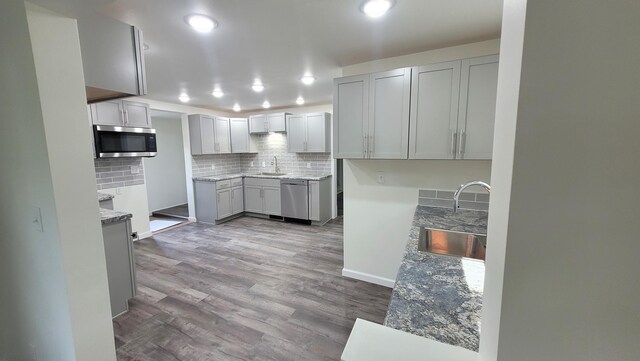 203 E Mill St, Athens, MI 49011 - kitchen featuring a sink, stainless steel appliances, backsplash, gray cabinets, and wood finished floors