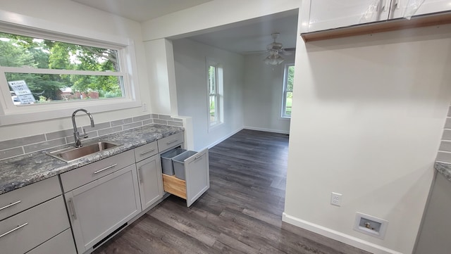 kitchen featuring dark wood-type flooring, sink, dark stone countertops, and a healthy amount of sunlight